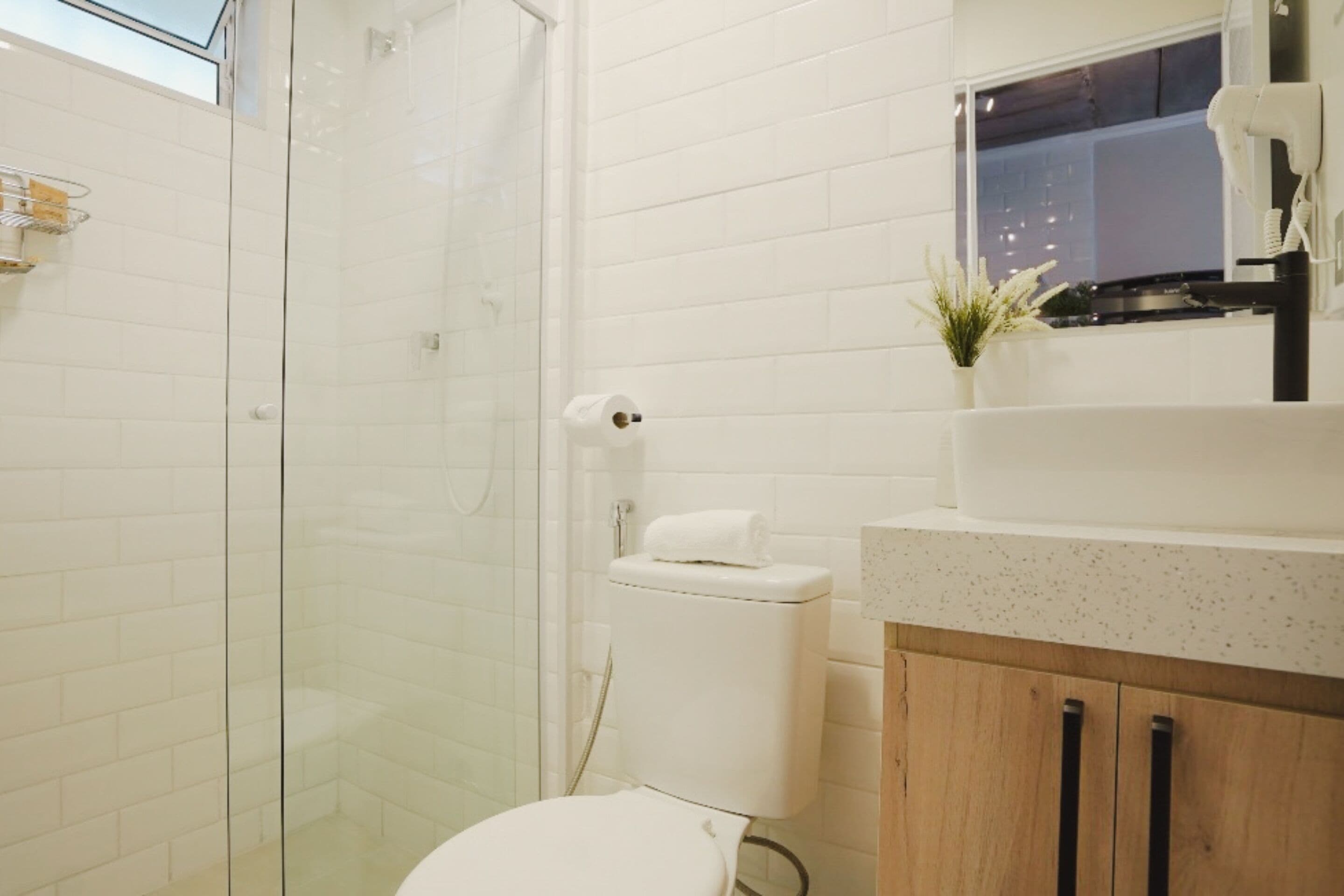 Une salle de bain moderne avec une douche à parois de verre, des toilettes blanches et un meuble-lavabo en bois avec un évier.