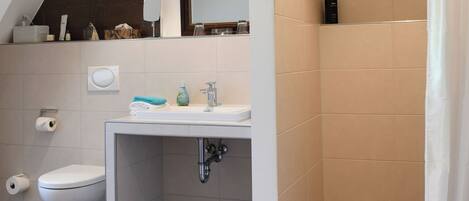 A modern bathroom with a shower, toilet, and sink.