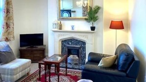 Ein Wohnzimmer mit Kamin, Fernseher, Sofa und Lampe.