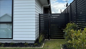 A modern house with white siding and a black fence. - Brand New Cosy and Convenient Retreat in Taupo  (Taupo)
