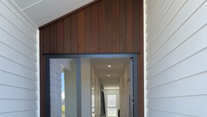 A modern entryway with a glass door, a wooden sloped ceiling, and a carpeted floor. - Brand New Cosy and Convenient Retreat in Taupo  (Taupo)