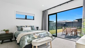 A modern bedroom with a large sliding glass door leading to a patio area. - Brand New Cosy and Convenient Retreat in Taupo  (Taupo)