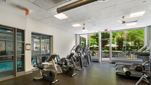 A gym with treadmills, elliptical machines, and weight equipment. There is a glass door leading to a pool area. - Crystal City Apartments near Reagan Airport - We Host (Arlington)