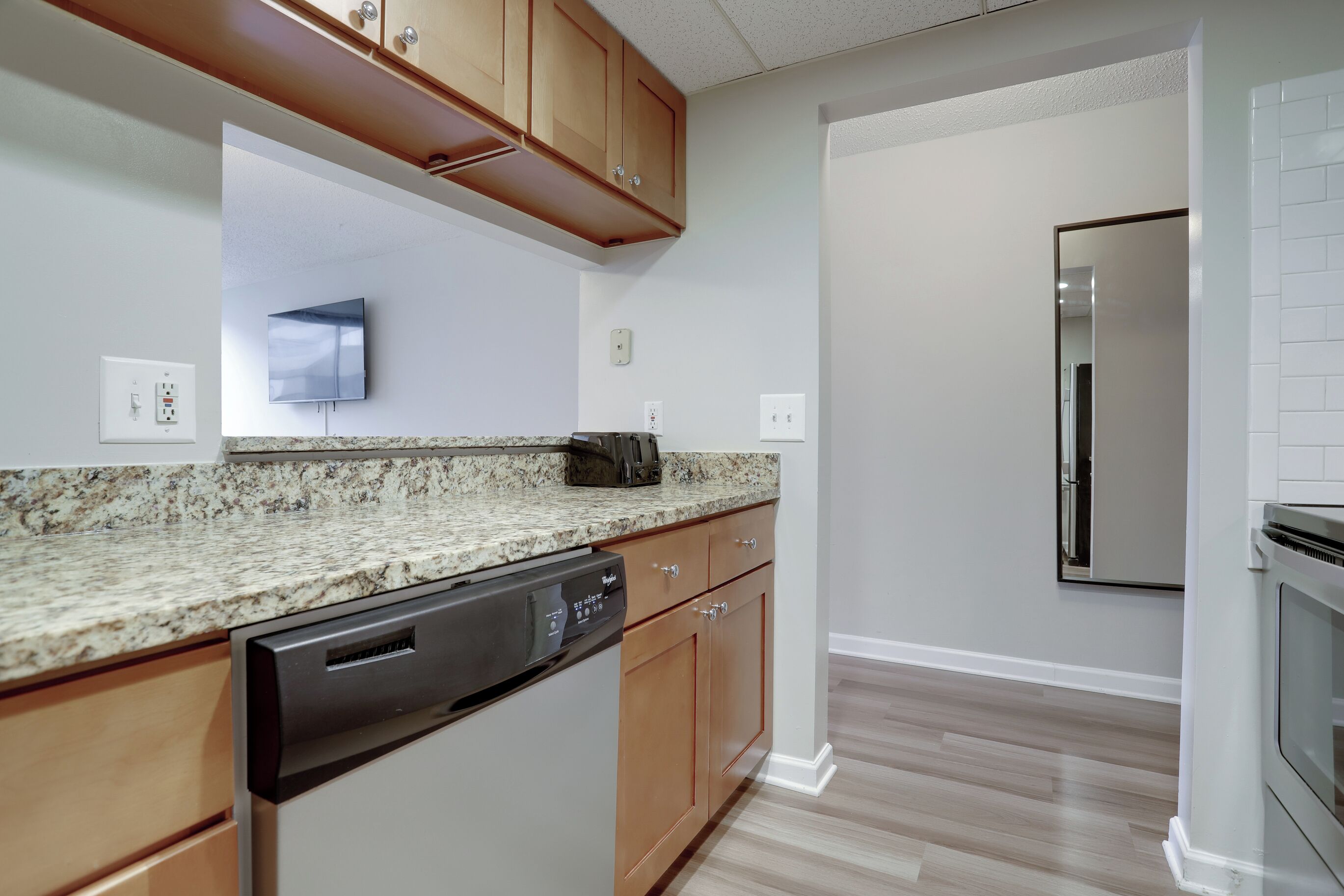 A kitchen with granite countertops, wooden cabinets, a dishwasher, a built-in oven, and a stainless steel refrigerator.