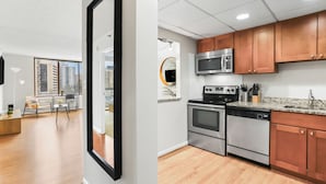A modern kitchen with stainless steel appliances, wooden cabinets, and a granite countertop.