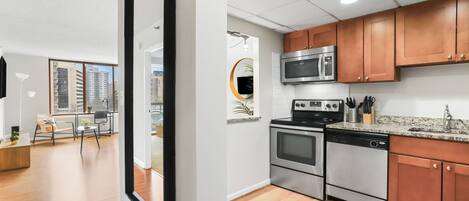 A modern kitchen with stainless steel appliances, wooden cabinets, and a granite countertop.