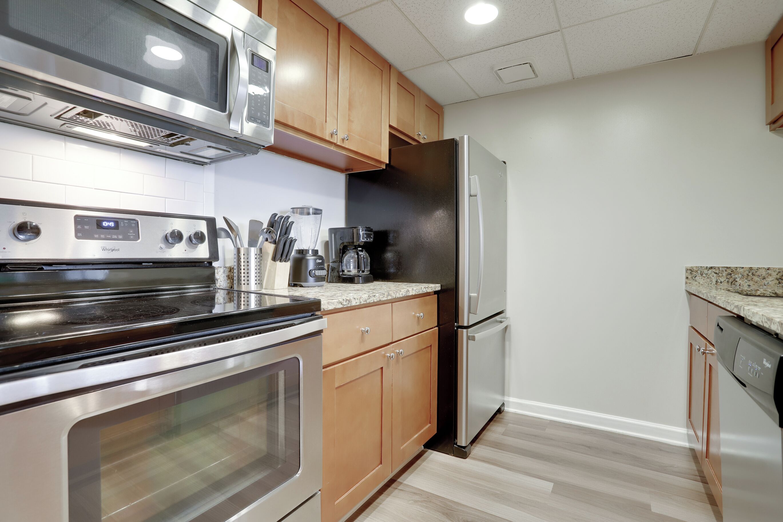 A modern kitchen with stainless steel appliances, wooden cabinets, and a granite countertop.