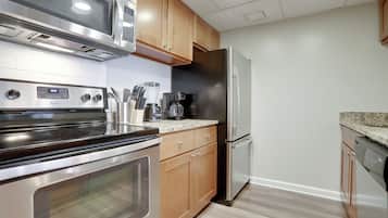 A modern kitchen with stainless steel appliances, wooden cabinets, and a granite countertop.
