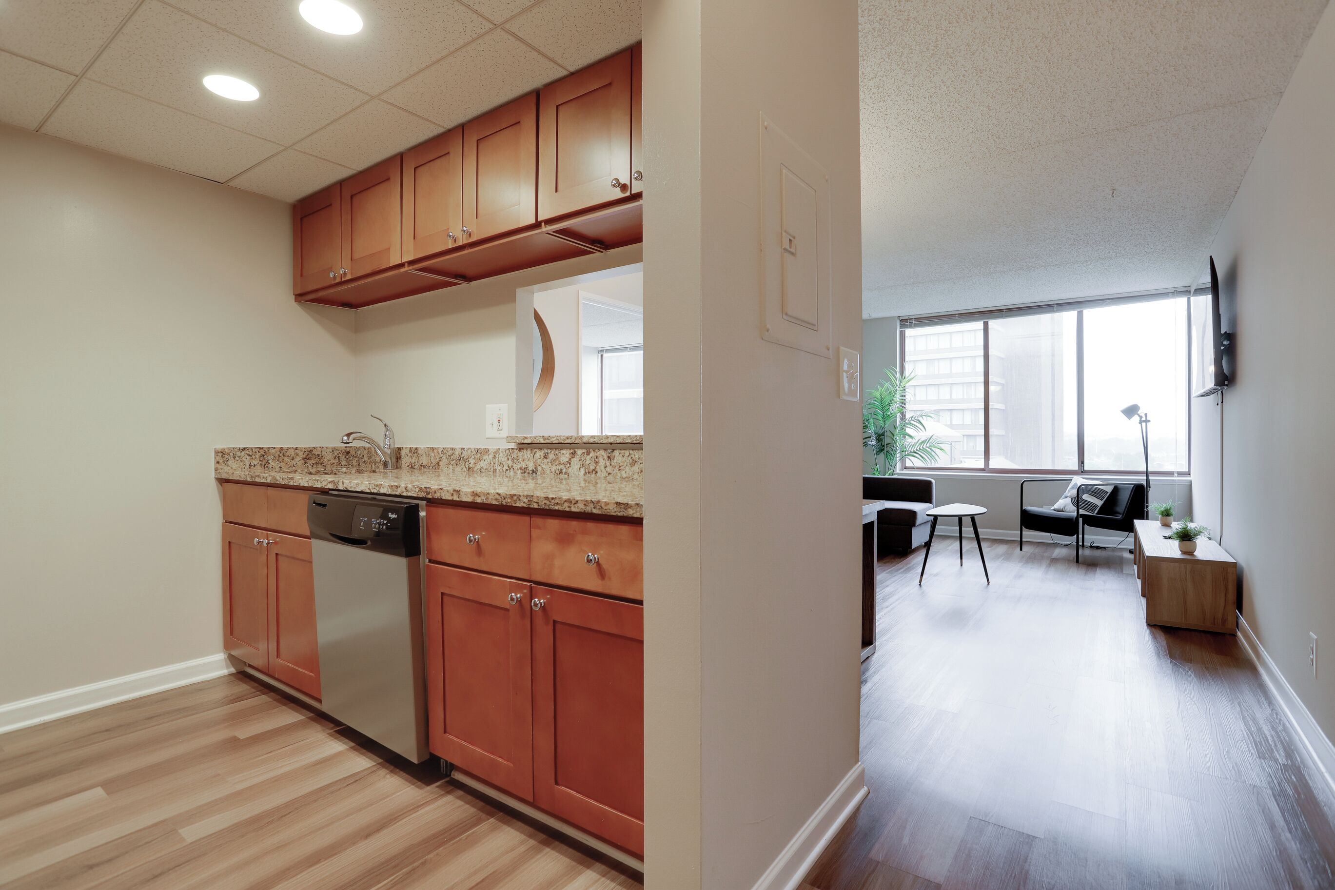 A modern kitchen with wooden cabinets, a dishwasher, and a granite countertop.