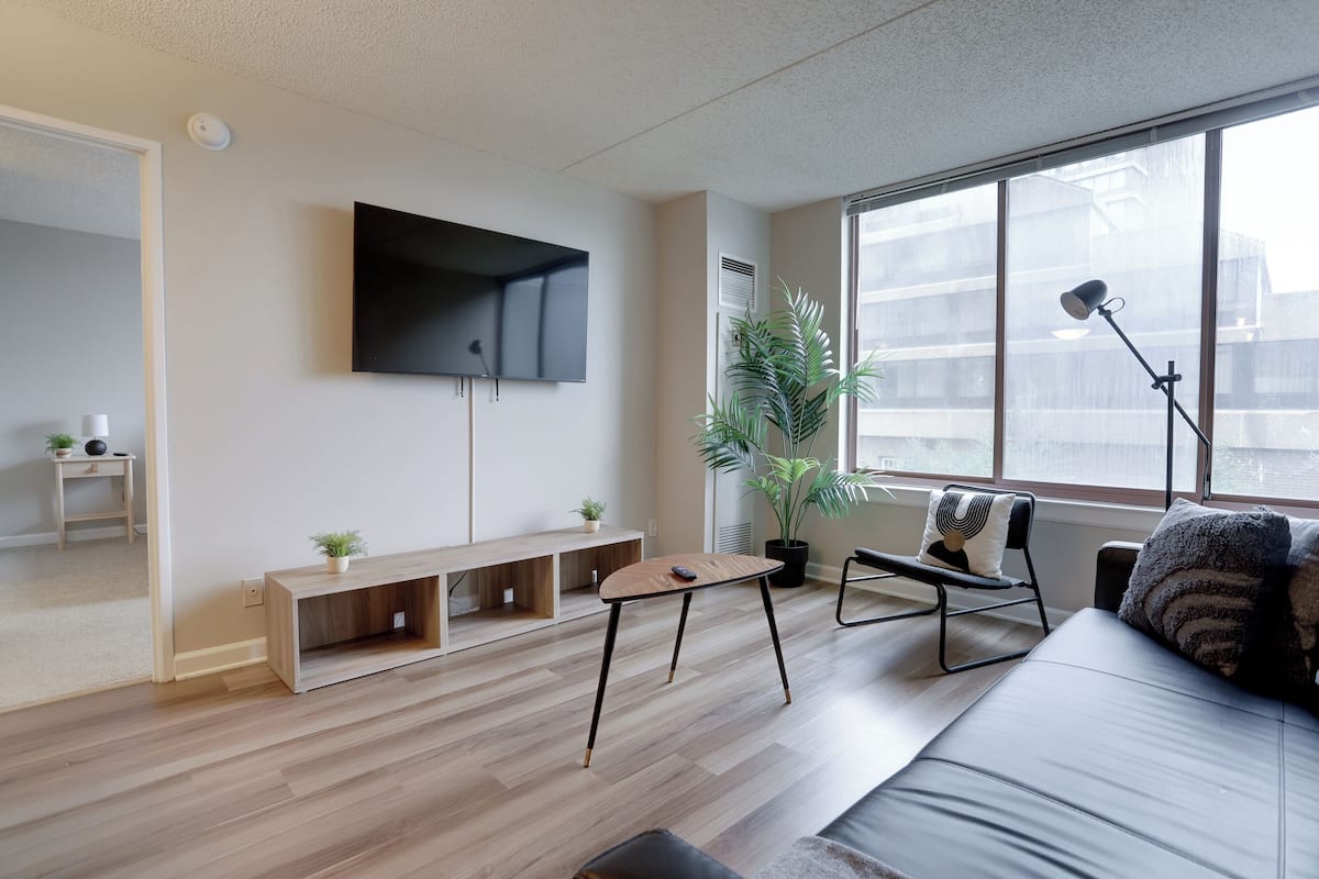Un salon moderne avec un téléviseur à écran plat, un canapé, une table basse et une plante en pot.