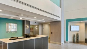 A reception desk with a sign reading "Luxury Apartments," a modern interior with recessed lighting, and a digital display on the wall. - Crystal City Apartments near Reagan Airport - We Host (Arlington)