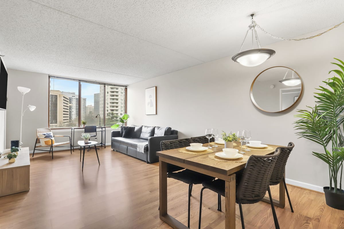 Un salon moderne avec un coin repas, de grandes fenêtres et une vue sur la ville.