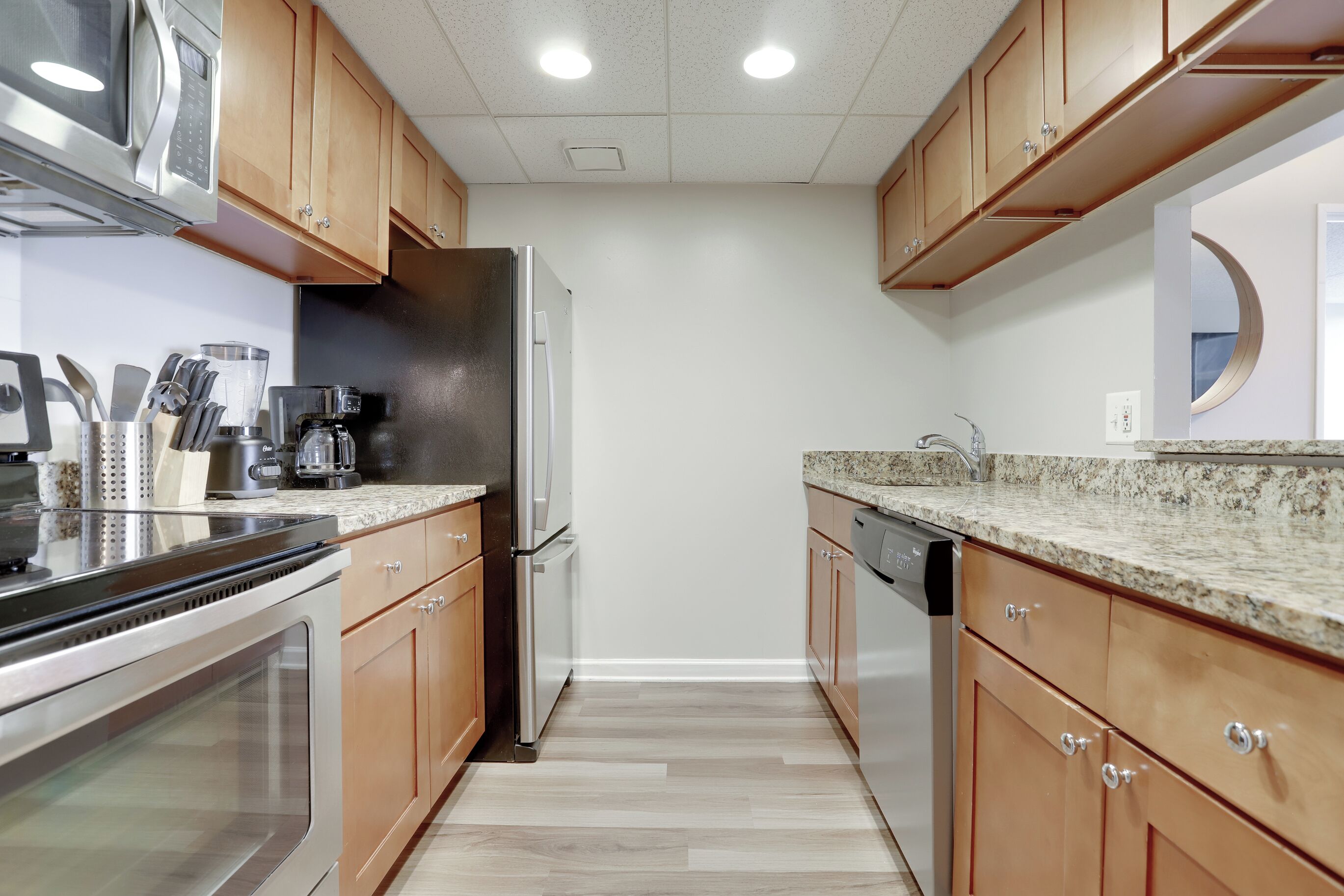 A modern kitchen with wooden cabinets, stainless steel appliances, and a granite countertop.