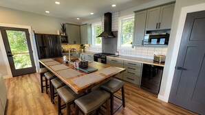 A modern kitchen with a central island, wooden flooring, and built-in appliances.