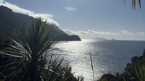 Un paysage côtier avec un ciel dégagé, un soleil éclatant et une vue sur l’océan.
