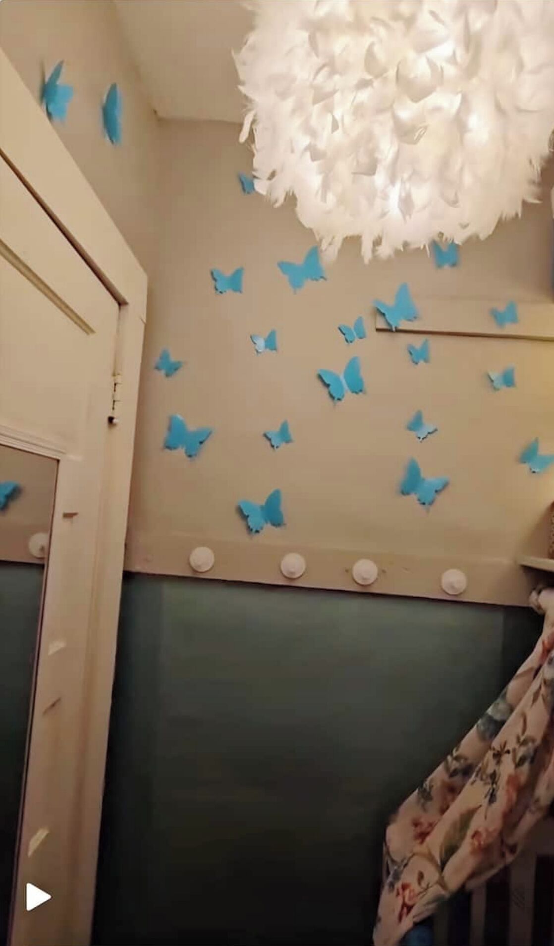 A room with a white ceiling, a fluffy white light fixture, and blue butterfly wall decals.