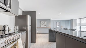A modern kitchen with a stove, oven, and microwave, a dining area with a table and chairs, and a large window providing natural light. - Blueground Mexico City JVM 429 (Mexico City)