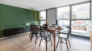 A dining area with a table set for four, a radiator, and a large window with a view of buildings. - Blueground Mexico City JVM 429 (Mexico City)