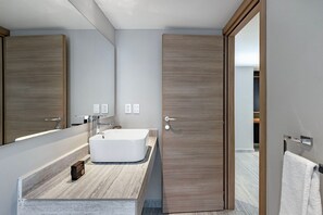 Ein modernes Badezimmer mit einem großen Spiegel, einer freistehenden Badewanne und einer Holztür.