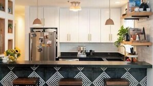 A modern kitchen with white cabinets, a central island with bar stools, pendant lighting, and a stainless steel refrigerator. - Park City Condo, Park City Condo In The Heart Of Park City (Park City)
