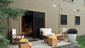 A building with a covered patio area featuring outdoor furniture, including chairs and a table. - Park City Condo, Park City Condo In The Heart Of Park City (Park City)
