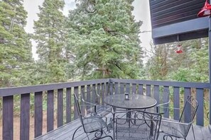 A deck with a round metal table and chairs, surrounded by a wooden railing, overlooking a forested area. - Red Door Mountain Retreat Near Park City (Silver Summit)