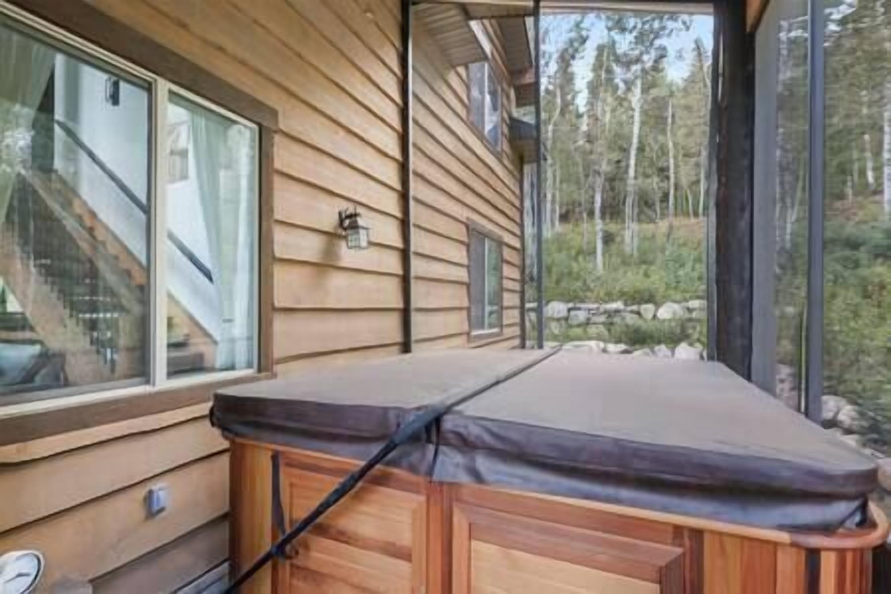 A wooden cabin with a covered deck, a window, and a view of trees.