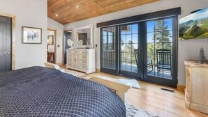 Ein Schlafzimmer mit einem großen Bett, einem Schminktisch und einer Glasschiebetür, die auf einen Balkon führt.