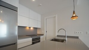 A modern kitchen with a stainless steel sink, a built-in oven, and a pendant light.