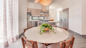 A modern kitchen with a round dining table, wooden chairs, and a hanging light fixture. - Vista Alta 208 in Punta Cana (Punta Cana)