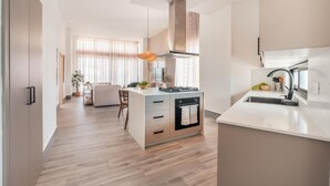 A modern kitchen with a central island, built-in oven, and stainless steel range hood. - Vista Alta 208 in Punta Cana (Punta Cana)