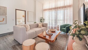 A modern living room with a beige sofa, a wooden coffee table, and a green armchair. - Vista Alta 208 in Punta Cana (Punta Cana)