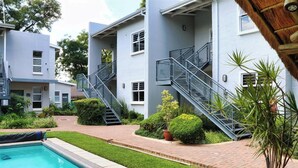 A modern building with a swimming pool, a covered outdoor area, and a staircase leading to an upper level. - Apartments 125 (Gaborone)