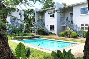 Un edificio residencial con piscina, escaleras y áreas verdes.