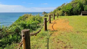 A coastal path with a chain-link fence, leading to a bench overlooking the sea. - Sea Whispers - ocean outlook, walk to 3x beaches (Port Macquarie)