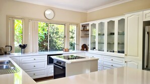 A modern kitchen with white cabinetry, a central island, and a built-in oven. - Sea Whispers - ocean outlook, walk to 3x beaches (Port Macquarie)