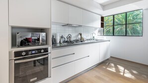 A modern kitchen with white cabinetry, stainless steel appliances, and a large window with a view of greenery. - Blueground Oaxaca CDMX (Mexico City)