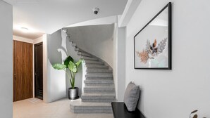 A modern interior with a staircase, a potted plant, a framed artwork, and a bench. - Blueground Oaxaca CDMX (Mexico City)