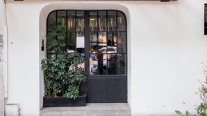 A black door with a glass panel, a small planter with green plants, and a white wall. - Blueground Oaxaca CDMX (Mexico City)