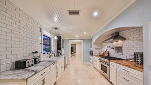 Een moderne keuken met witte metrotegels, een marmeren aanrechtblad en een roestvrijstalen afzuigkap.