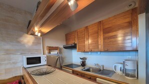 A compact kitchen with wooden cabinets, a microwave, a sink, and a coffee maker.