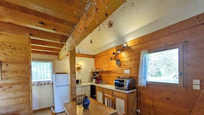 A wooden cabin interior with a kitchen, dining area, and a window with a view. - Chalet nordique, 6 personnes (La feclaz)