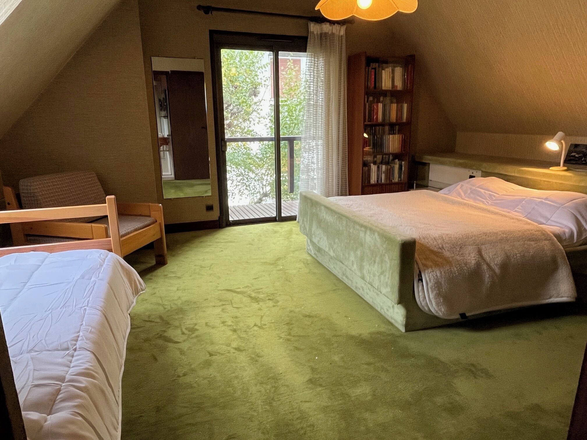Un dormitorio acogedor con dos camas, una estantería y una ventana con vistas a la vegetación.