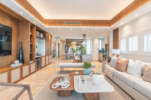 A modern living room with a sofa, coffee table, and a dining area in the background.
