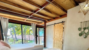 A bedroom with a large bed, a view of the outdoors, and a wooden ceiling. - Nochtli Beach House (Playas Negras)
