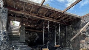 A stone structure with a metal roof and wooden beams, featuring a stone staircase and a swing set. - Nochtli Beach House (Playas Negras)