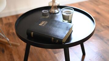 A small round table with a book, a candle, and dried plants.