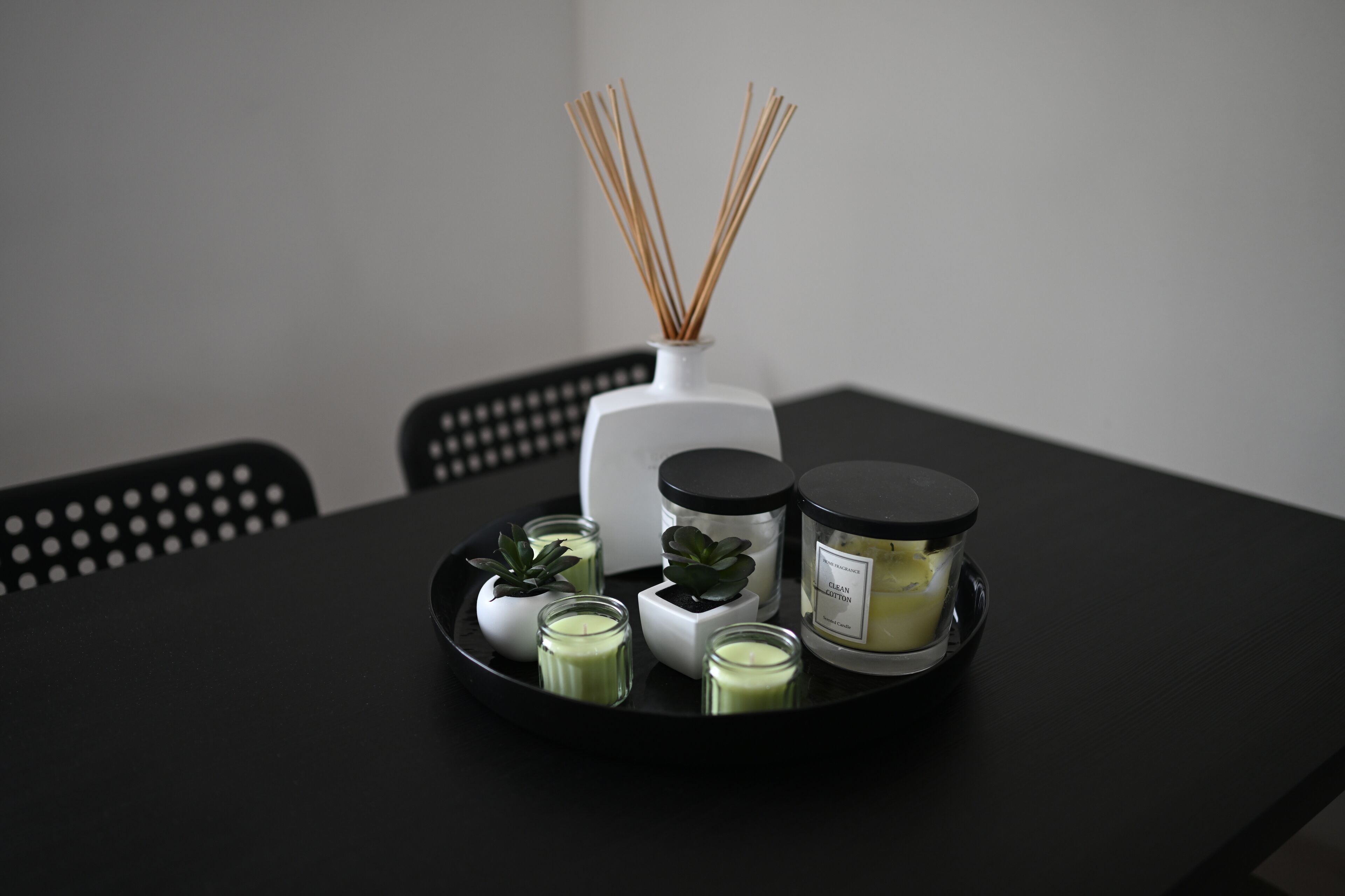 Una bandeja con diversas velas aromáticas y difusores de aroma en una mesa negra.