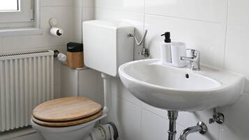 Un baño moderno con inodoro, lavamanos y espejo.