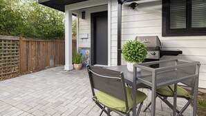 A patio with a grill, a table, and chairs. - Chic Garden Suite (Victoria)